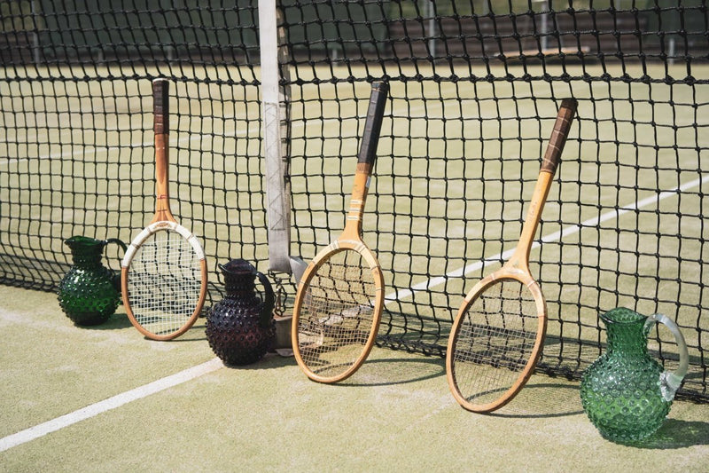 Violet Hobnail Jug on a tennis court surrounded by a net and tennis rackets 