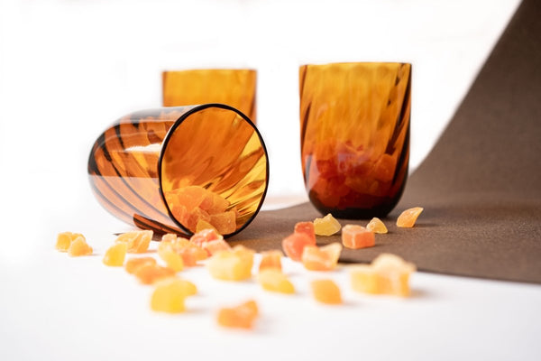 Amber Marika Tumblers on a brown tablecloth with slivers of dried orange fruit