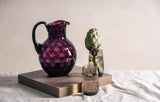 Violet Kugel Jug on a square wooden piece with glasses and artichoke
